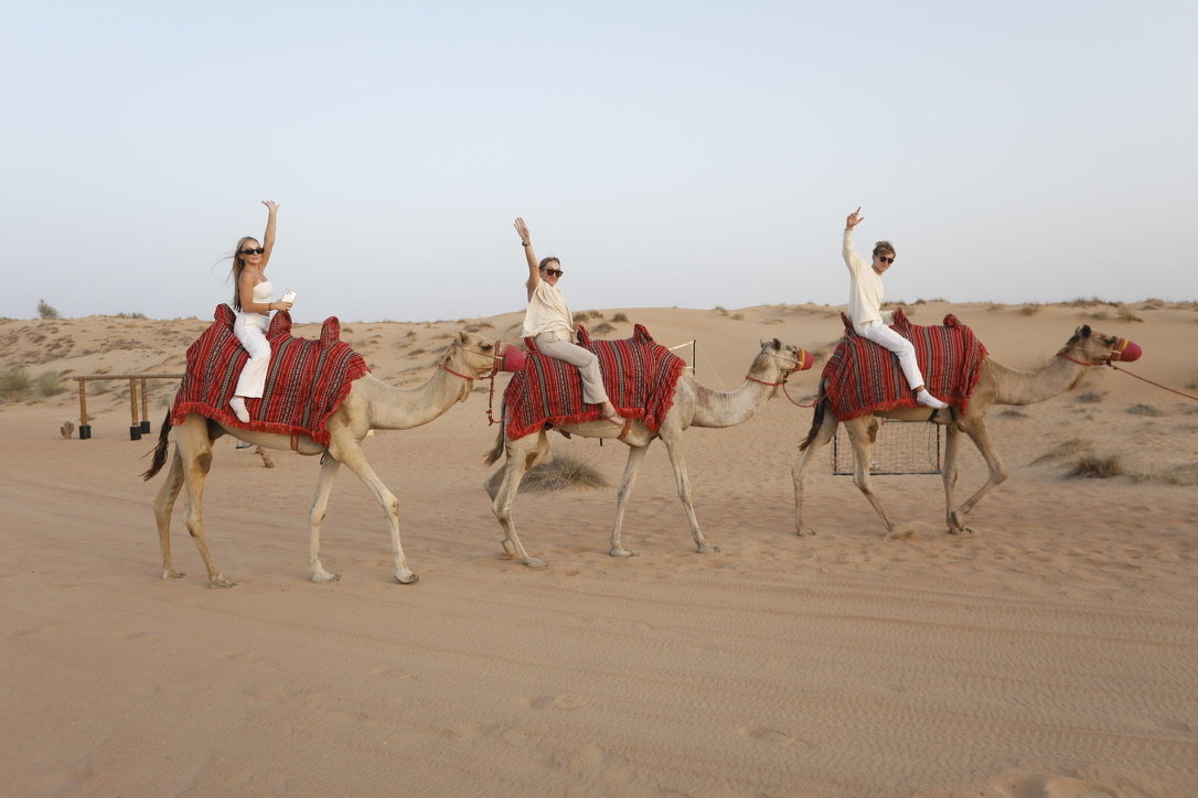 Miles and family riding camels across the desert in Dubai