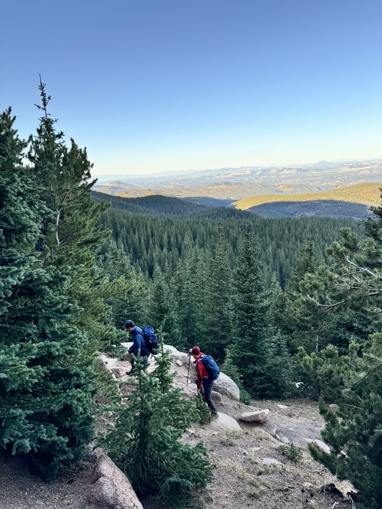 Hikers on a forested trail with mountain views at Pikes Peak